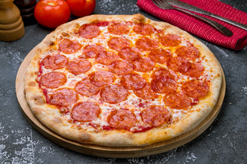 Pepperoni pizza on the board on grey concrete table