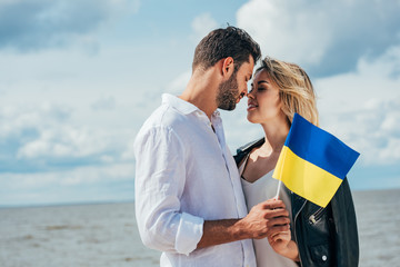 attractive woman and handsome man holding ukrainian flag outside