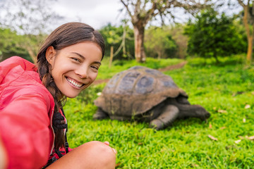 Galapagos Adventure travel tourist on Galapagos Islands taking selfie photo by Giant Tortoises on...