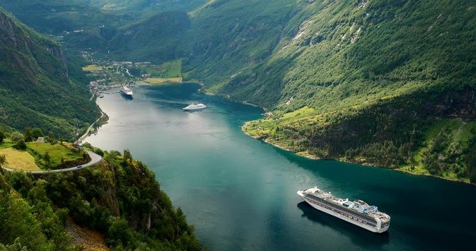 Geirangerfjord, Norway. Touristic Ship Ferry Boat Cruise Ship Liner Floating Near Geiranger In Geirangerfjorden In Sunny Summer Day. Famous Norwegian Landmark And Popular Destination. Zoom Out