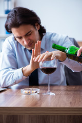 Male employee drinking alcohol and smoking cigarettes at workpla