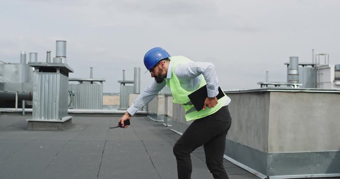 Funny good looking architect on the rooftop of construction site dancing and feeling very excited wearing a safety helmet and business clothes