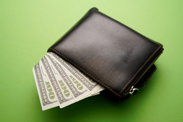 A wallet with dollar bills on green background