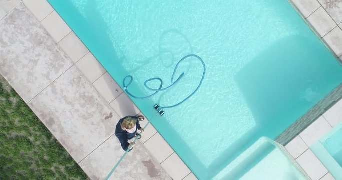 Overhead Aerial of Woman Vacuuming Swimming Pool