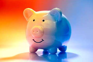 Smiling Piggybank on red and blue background. Saving vs spending money concept.