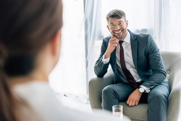 selective focus of journalist talking with handsome businessman in suit and glasses