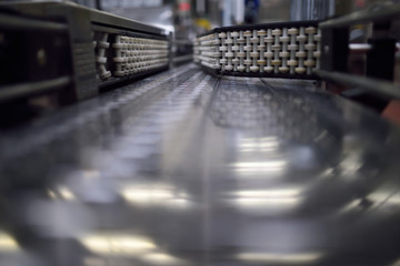 Close up of a steel conveyor belt at a bottling station in a brewery plant