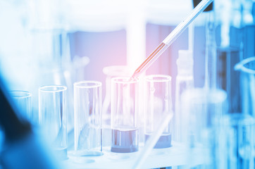 A pipette dropping sample into a test tube,abstract science background