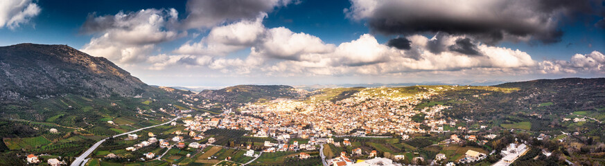 Obraz premium Agricultural field with town and mountain against cloudy sky