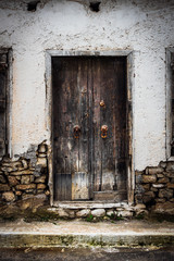 Weathered wooden door with door knob and stone wall