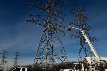 Hydro linemen on boom lifts working on high voltage power line towers