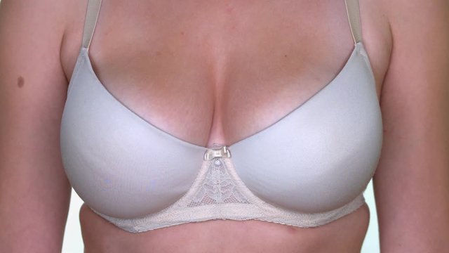 Closeup of a womans chest wich is wearing white lingerie.