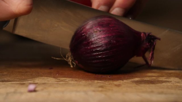 Slow motion - red onion being sliced by sharp knife, chef cutting vegetables  