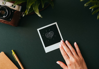 Female hand holds a polaroid picture with a heart
