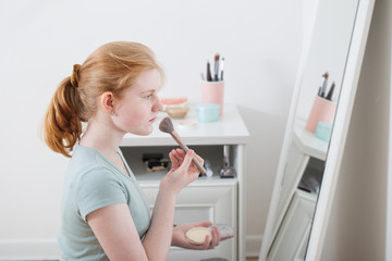 Obraz na płótnie Canvas teen girl powders her face