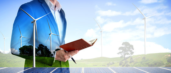Double exposure graphic of business people working over wind turbine farm and green renewable...