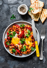 Shakshuka with baked sweet peppers and chickpeas on a dark background, top view