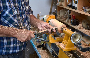 The woodturner work. Man's arms with cutter in action.