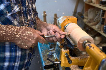 The woodturner work. Man's arms with cutter in action.