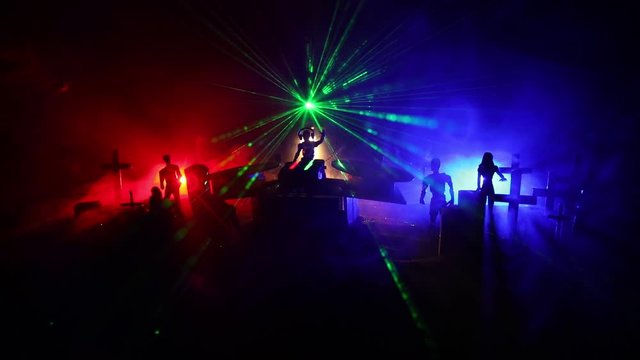Happy Halloween horror party concept. Scary view of dancing zombies at cemetery with Dj and club lights. Creative artwork decoration. Useful as a party poster or greeting card. Selective focus