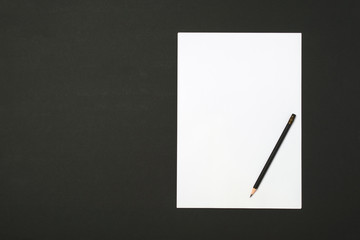 Blank paper sheet and pencil for mock up on a dark background