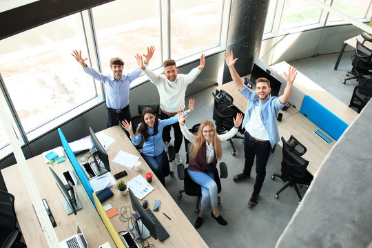 Top view of young modern colleagues in smart casual wear working together while spending time in the office.