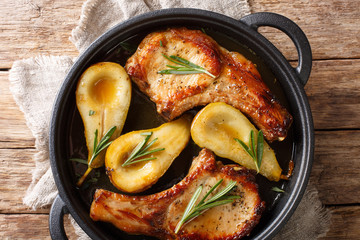 Holiday recipe for baked pork chops with pears and rosemary in honey sauce served in a pan close-up. Horizontal top view