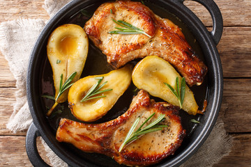 Fried pork chops with ribs with pears and rosemary in honey sauce served in a pan close-up. Horizontal top view