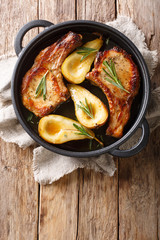 Autumn food pork chops with ribs baked with pears and rosemary in honey sauce in a pan close-up. Vertical top view
