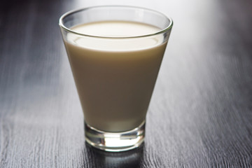 Milk in a glass cup on a wooden background.