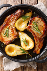 Baked pork chops with pears, rosemary and honey in a pan close-up. Vertical top view