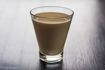 Milk in a glass cup on a wooden background.