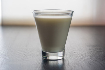 Milk in a glass cup on a wooden background.