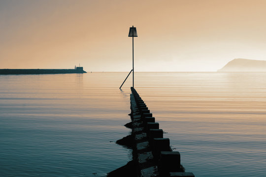 Groyne groin and beacon, sea defence,  at Fishguard on the coast of Wales. With colour toning