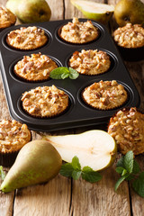 Autumn vegetarian pear muffins with walnuts in a baking dish close-up. vertical