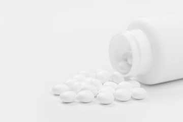 Pill bottle spilling medical pills onto surface isolated on a white background.