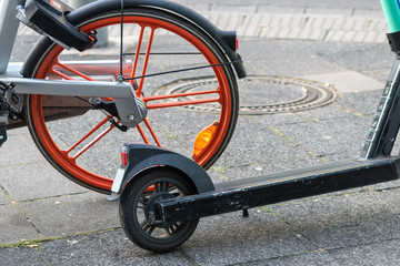 Obraz premium Leihfahrrad eines Bike-Sharing-Anbieters und E-Scooter stehen nebeneinander und repräsentieren emissionsfreie Beförderung und Fortbewegung in der Stadt als Alternative zum Auto