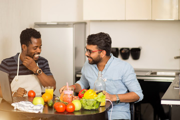 Two men using laptop in kitchen