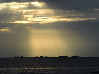 Beautiful warm sunlight shining during sunset time over the ocean with ships sailing view. Natural and inspirational concept