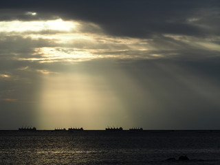 Beautiful warm sunlight shining during sunset time over the ocean with ships sailing view. Natural and inspirational concept