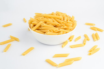 Dried penne Italian pasta in a round bowl ready to be cooked, isolated on white table, with view from above 