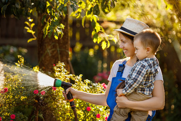 woman gardener with son watering garden