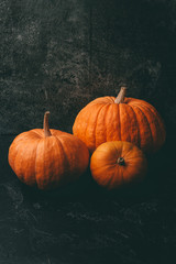 Photo of three orange pumpkins on black background, halloween celebration.