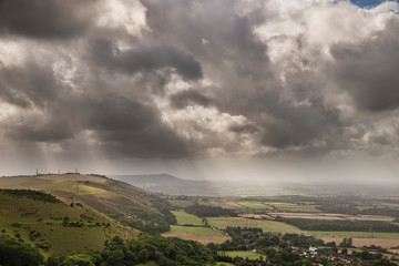 Stunning Summer landscape image of escarpment with dramatic storm clouds and sun beams streaming down