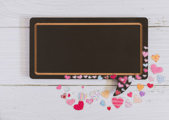 Flat lay of black blank speech bubble wooden sign on white marble background with many tiny hearts. Concept of couple, family, friend, lover and Valentine. Love photo frame