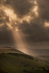Stunning Summer landscape image of escarpment with dramatic storm clouds and sun beams streaming down