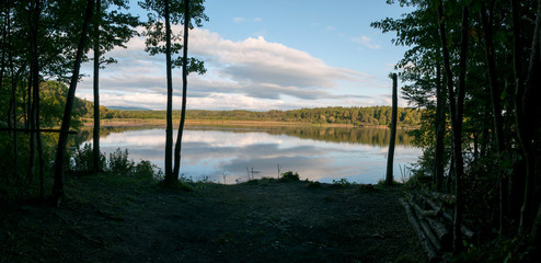 Beautiful panorama of autumn lake against the background of forest and sunny sky