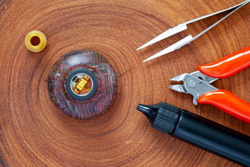 single micro coil with cotton in rebuildable dripping atomizer on stabilized wood atty stand with...
