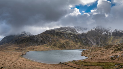 Beautiful moody Winter landscape image of Llyn Idwal and snowcapped Glyders Mountain Range in Snowdonia