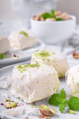 Cotton candy with pistachio on ceramic plate on white wooden table